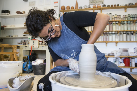 Woman working with a pottery wheel in her workshop stock photo