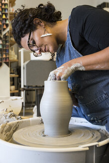 Woman working with a pottery wheel in her workshop - ABZF01274