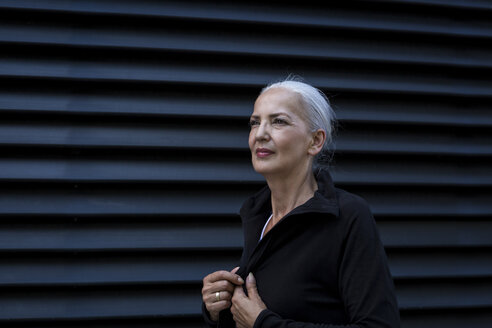 Woman wearing black tracksuit top in front of black background - JUNF00620