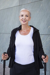 Portrait of smiling woman with walking sticks - JUNF00621