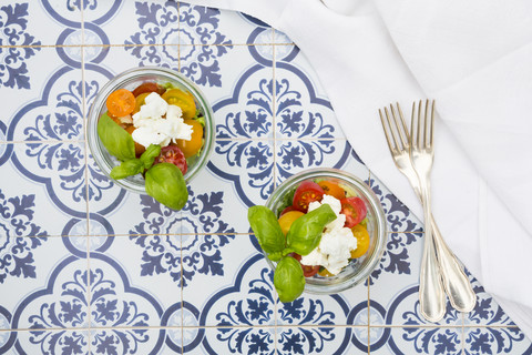 Teo Gläser mit Blattsalat mit Ziegenfrischkäse und Tomaten auf Fliesen, lizenzfreies Stockfoto