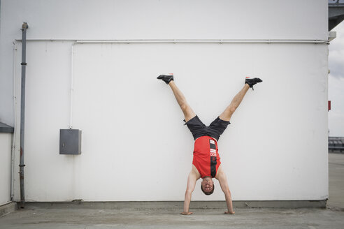 Man doing handstand against wall - ASCF00656