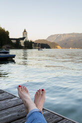 Österreich, Sankt Wolfgang, Füße einer Frau auf einem Steg am See - JUNF00629