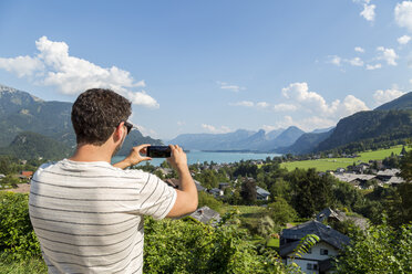 Austria, Sankt Wolfgang, man taking picture of Wolfgangsee - JUNF00631