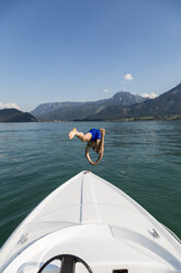 Austria, Sankt Wolfgang, man jumping from boat into lake - JUNF00635