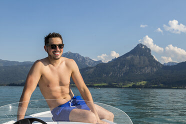 Austria, Sankt Wolfgang, man sitting on boat in lake - JUNF00637