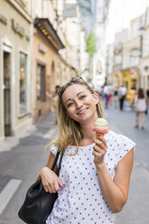 Austria, Salzburg, smiling woman on shopping street with ice cream cone - JUNF00648