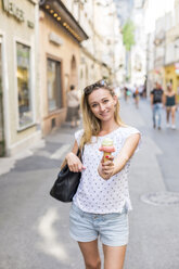 Austria, Salzburg, woman on shopping street offering her ice cream cone to viewer - JUNF00649