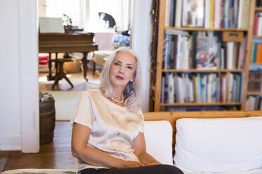 Portrait of mature woman sitting on couch at home - JUNF00653