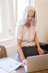 Geschäftsfrau arbeitet mit Laptop zu Hause - JUNF00658