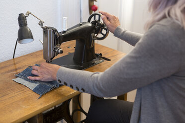 Woman working at sewing machine at home, partial view - JUNF00683