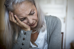 Portrait of sad woman with head in her hand at home - JUNF00691