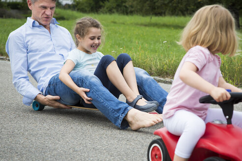 Father and daughter longboarding in garden - JTLF00115