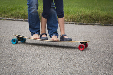Father and daughter longboarding in garden - JTLF00117