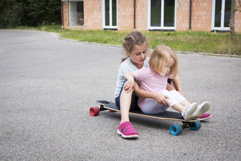 Zwei Schwestern sitzen auf einem Longboard - JTLF00120