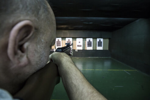 Man aiming with a carbine in an indoor shooting range - ABZF01277