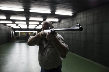 Mann beim Zielen mit einem Karabiner in einer Schießhalle - ABZF01278