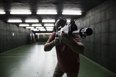 Mann beim Zielen mit einer taktischen Waffe in einer Schießhalle - ABZF01283