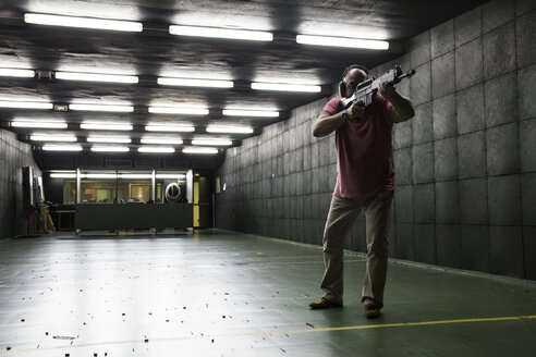 Mann beim Zielen mit einer taktischen Waffe in einer Schießhalle - ABZF01285