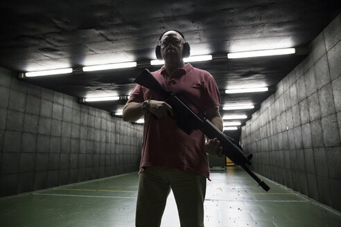 Mann hält eine taktische Waffe in einer Schießhalle - ABZF01286