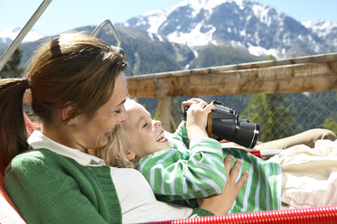 Glückliche Mutter und Tochter entspannen sich auf einer Panoramaterrasse in den Bergen - FSF00504