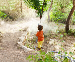 Back view of little boy playing with garden hose - VABF00778