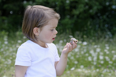 Kleines Mädchen beobachtet Schlange, die sie in ihrer Hand hält - LBF01484