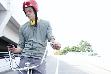 Jugendlicher auf dem Fahrrad mit Mobiltelefon - FSF00547