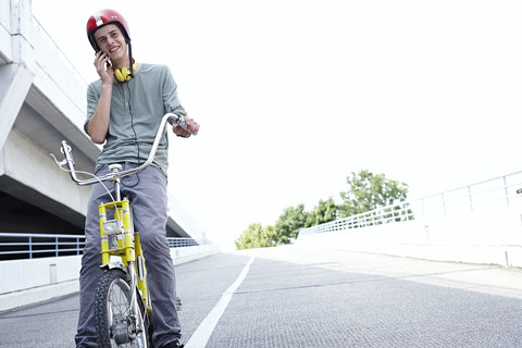 Jugendlicher auf dem Fahrrad, der mit einem Handy telefoniert, lizenzfreies Stockfoto