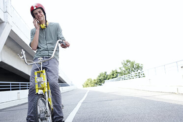 Jugendlicher auf dem Fahrrad, der mit einem Handy telefoniert - FSF00548