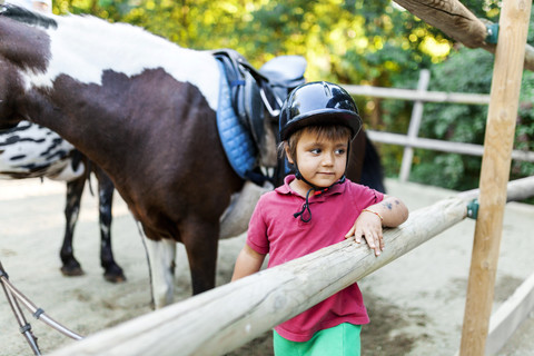 Kleiner Junge wartet auf den Beginn der Reitstunde, lizenzfreies Stockfoto