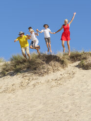 Family jumping from sand dune - LAF01763