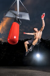 Kickboxer exercising with punch bag - STSF01103