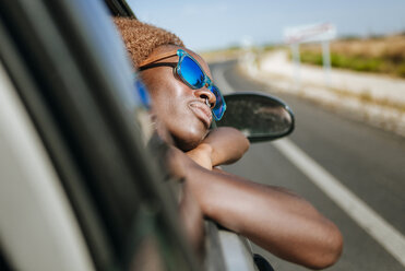 Junge Frau lehnt sich aus dem Autofenster - KIJF00789