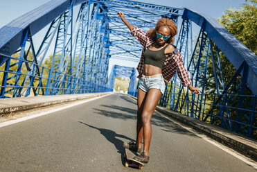 Junge Frau auf Skateboard auf einer Brücke - KIJF00817