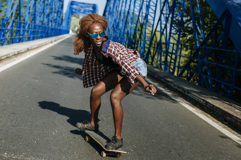 Junge Frau auf Skateboard auf einer Brücke, lizenzfreies Stockfoto