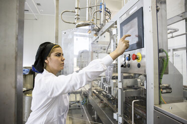 Frau bedient eine Maschine bei der Herstellung von Schokolade in einer Fabrik - ABZF01292