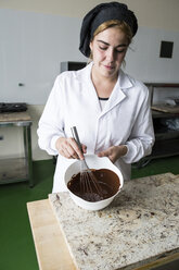 Frau verdickt geschmolzene Schokolade mit einem Schneebesen - ABZF01302