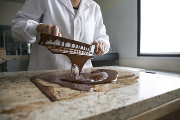 Frau temperiert geschmolzene Schokolade auf einer Marmorfläche - ABZF01303