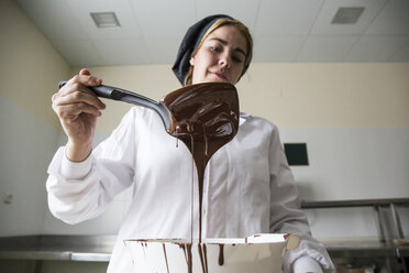 Frau prüft die Dicke der geschmolzenen Schokolade - ABZF01304