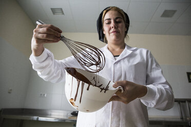 Frau prüft die Dicke der geschmolzenen Schokolade - ABZF01305