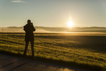 Deutschland, Bayern, Frau fotografiert Sonnenaufgang - TCF05105