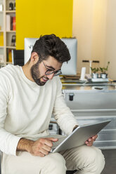 Junger Mann mit Laptop in einem modernen Büro - TCF05115