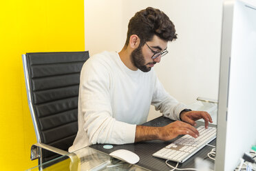 Junger Mann arbeitet mit Computer in einem Büro - TCF05117