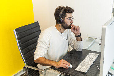 Junger Mann arbeitet mit Computer in einem Büro - TCF05118