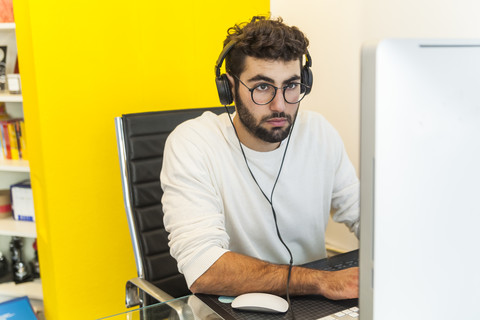 Junger Mann arbeitet mit Computer in einem Büro, lizenzfreies Stockfoto