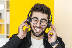 Porträt eines lachenden Mannes, der mit Kopfhörern Musik hört - TCF05122