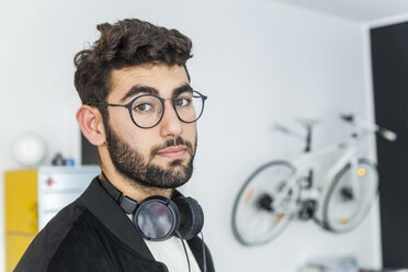 Porträt eines Mannes mit Brille und Kopfhörern in einem modernen Büro - TCF05123
