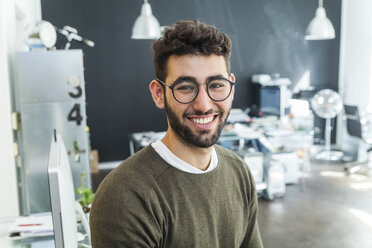Porträt eines lächelnden Mannes mit Brille in einem modernen Büro - TCF05127