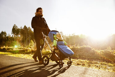 Father and son in buggy on a walk in forest - MFF03365